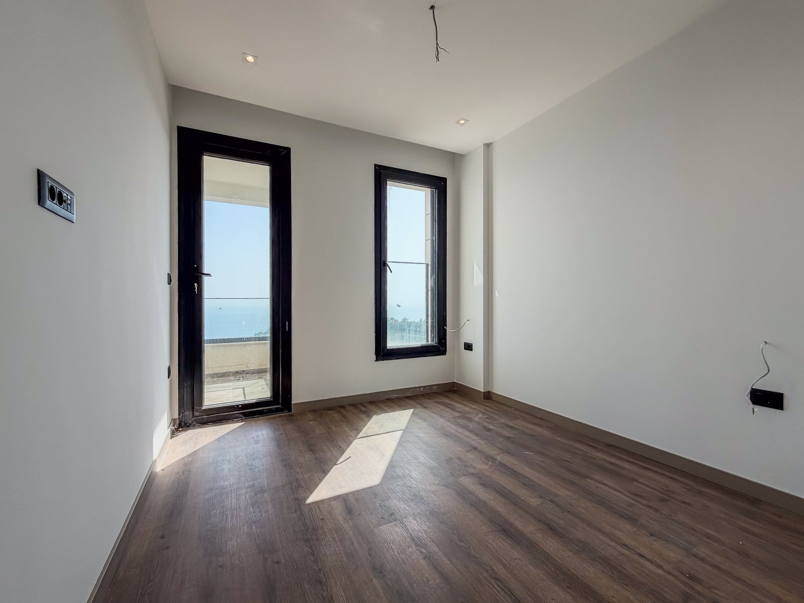 Bright unfurnished bedroom with a panoramic window and sea view in a new building in Budva, Montenegro