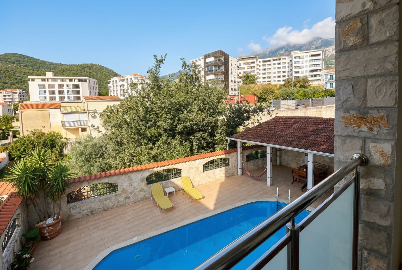 Pogled s balkona na otvoreni bazen, ležaljke i zonu za odmor u hotelu u Bečićima, Crna Gora.