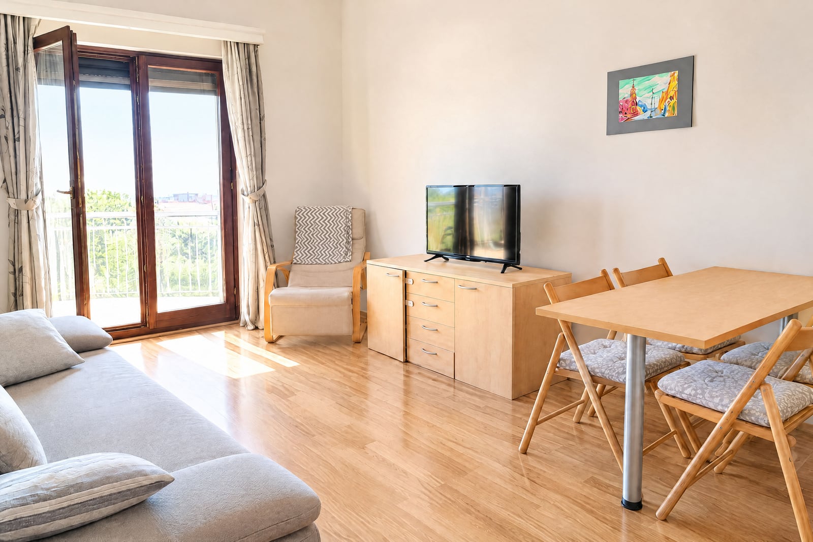 Bright living room with furniture, TV, and balcony in an apartment in Becici, Montenegro