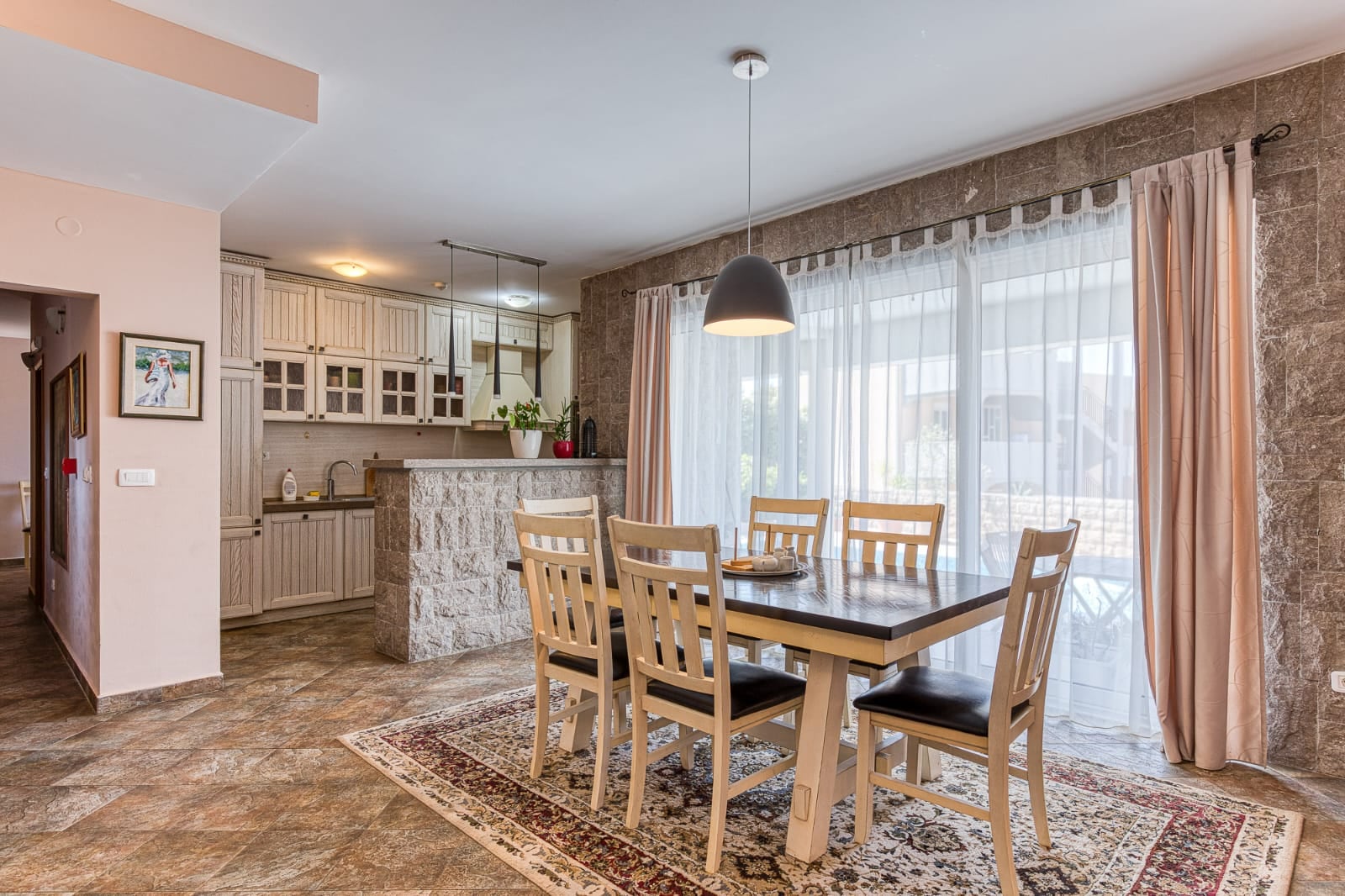 Cuisine-salle à manger avec finitions en pierre et coin repas dans une villa à Bečići, Monténégro. Intérieur moderne avec mobilier.