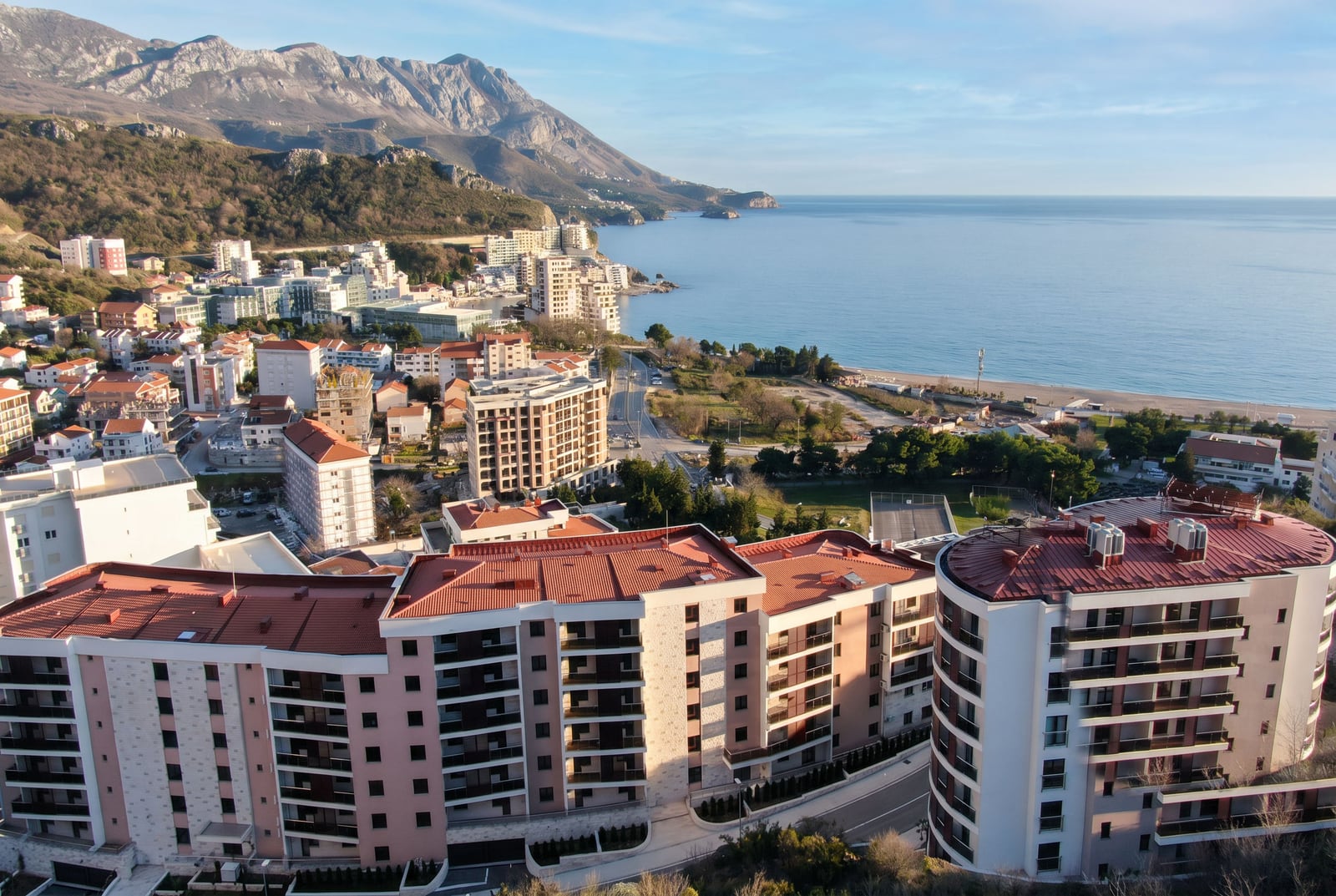 Panoramablick auf eine Wohnanlage in Bečići, Montenegro: moderne Häuser mit roten Dächern an der Adriaküste