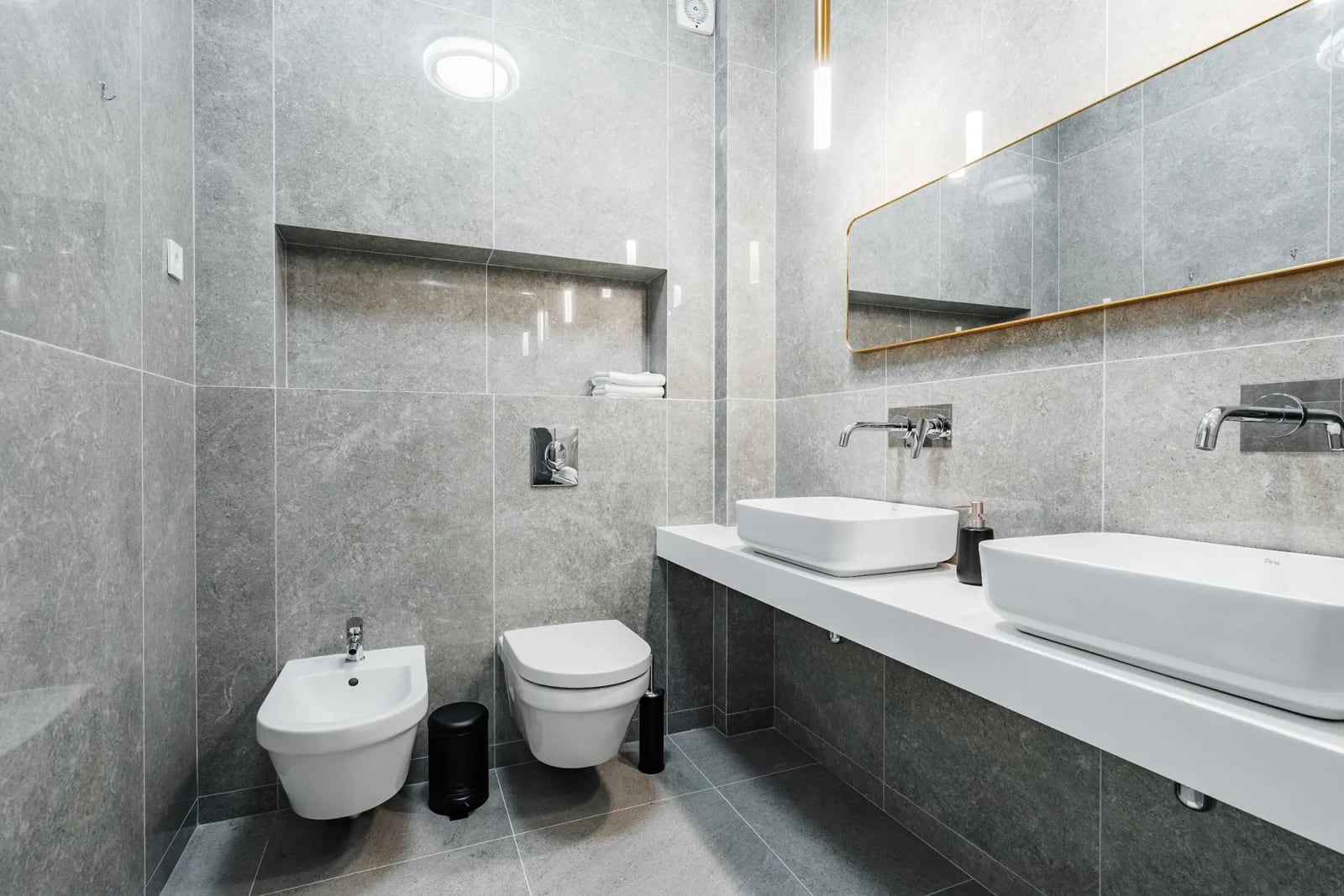 Modern bathroom with double vanity and bidet in a villa in Reževići, Montenegro, featuring grey porcelain tile finishes.