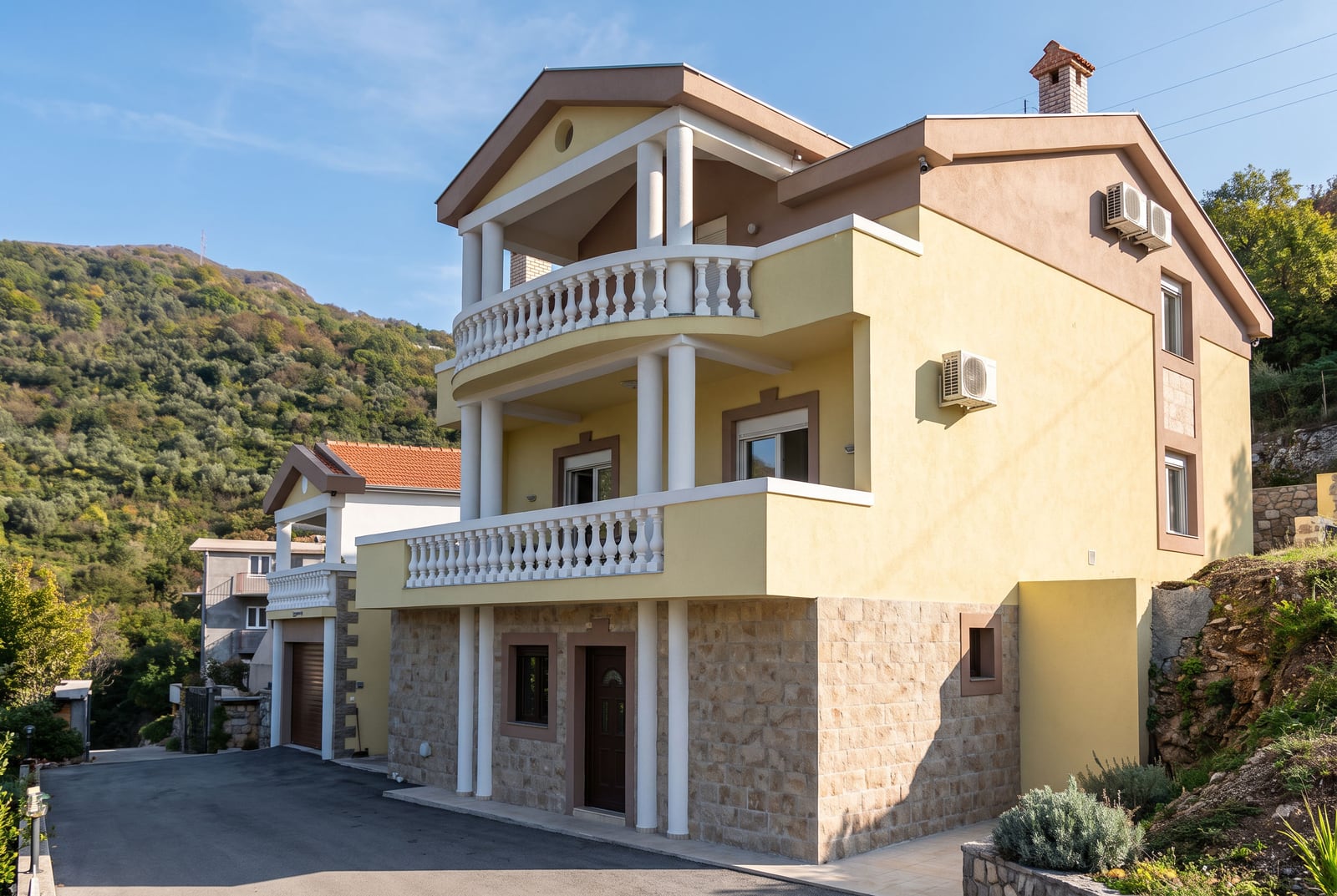 Three-story house in Tivat, Montenegro: facade with columns, balconies, and stone base finishing