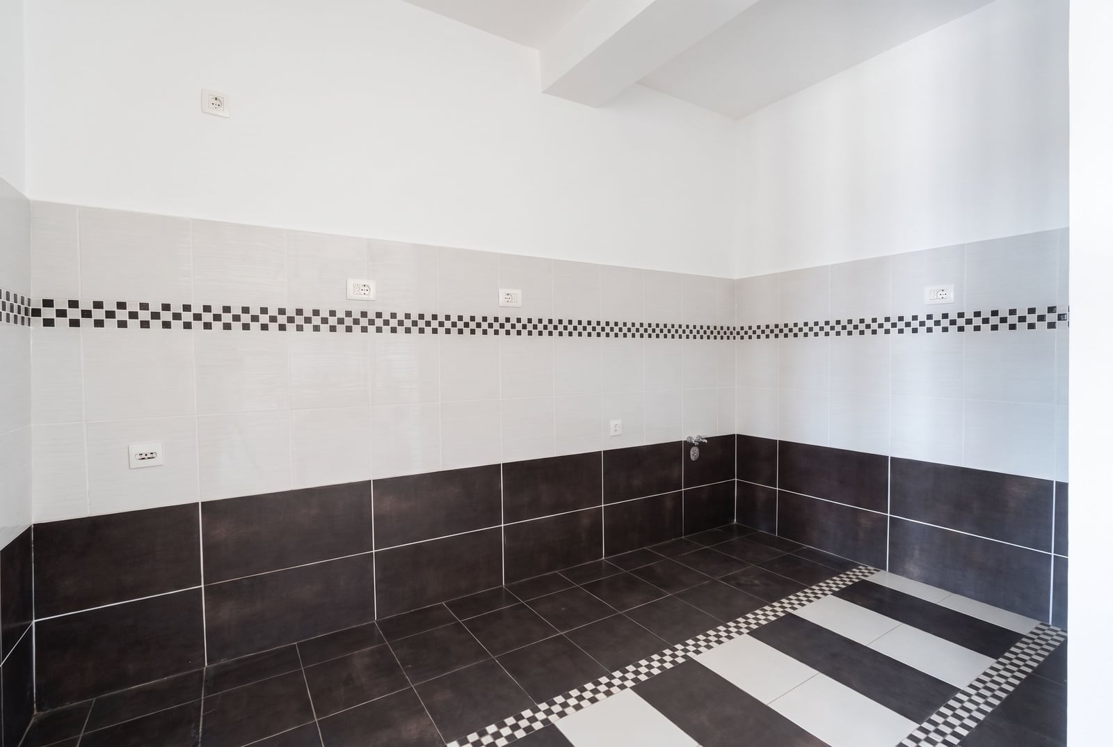 Rough finish bathroom with black and white tiles in an apartment in Petrovac, Montenegro.