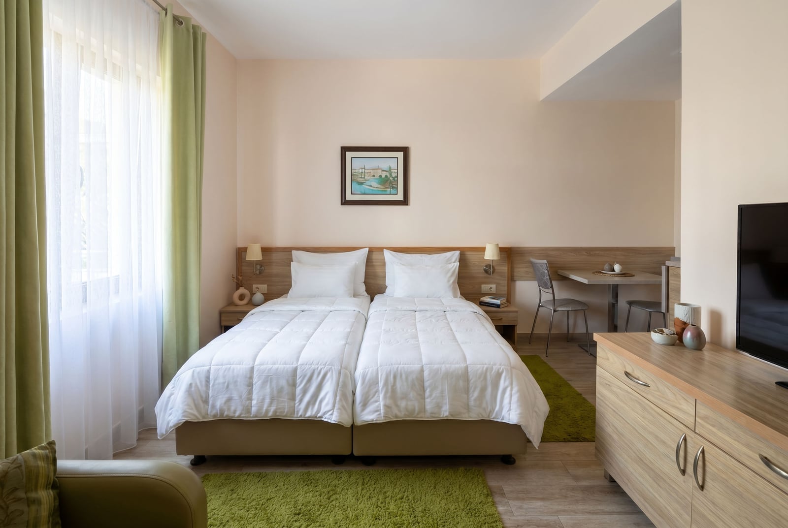 Cozy bedroom with two beds in an apartment in Rafailovici, Montenegro: light-colored furniture, TV, and dining area.
