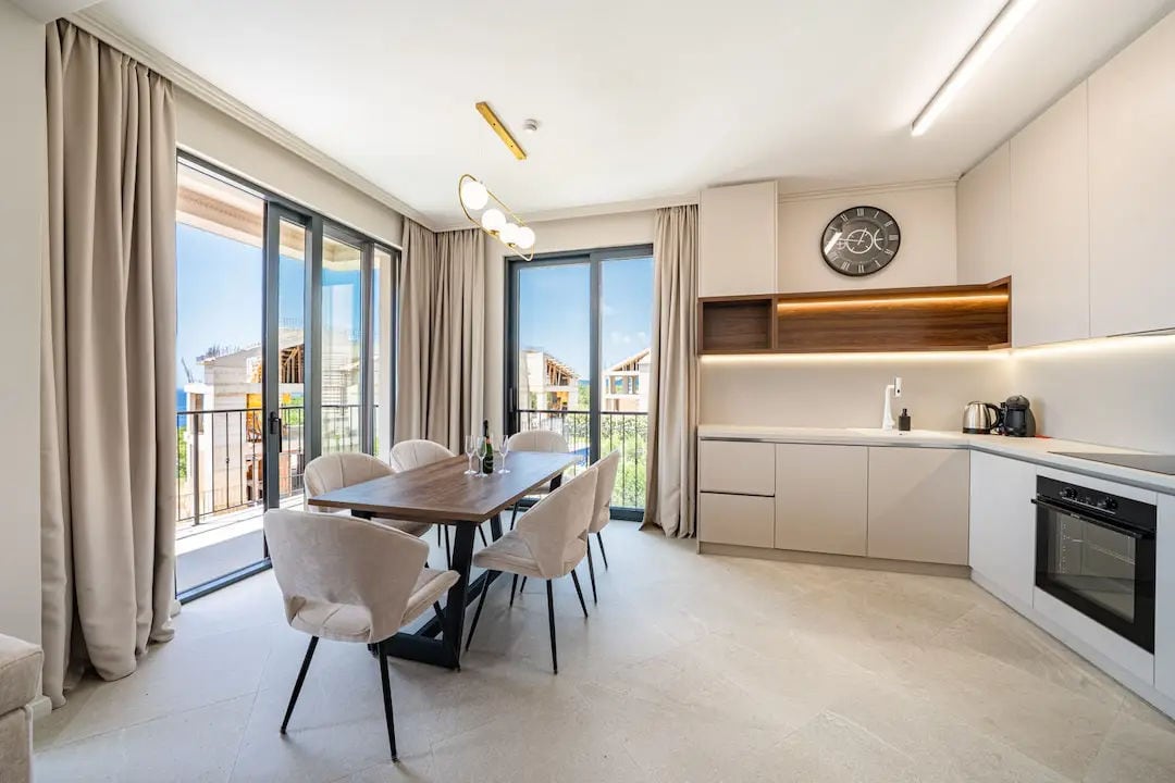 Cuisine-salle à manger moderne dans une villa à Reževići, Monténégro : intérieur lumineux, coin repas et baies vitrées panoramiques.