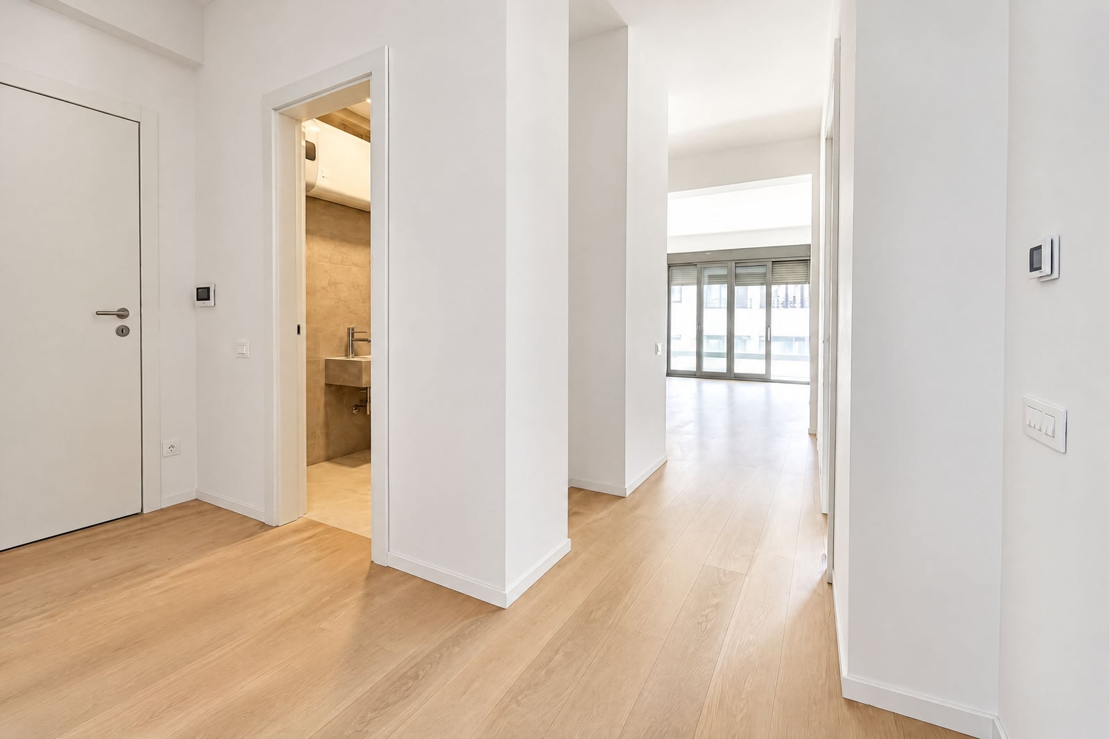 Bright hallway with white walls, parquet flooring, and a bathroom in a new apartment in Bečići, Montenegro