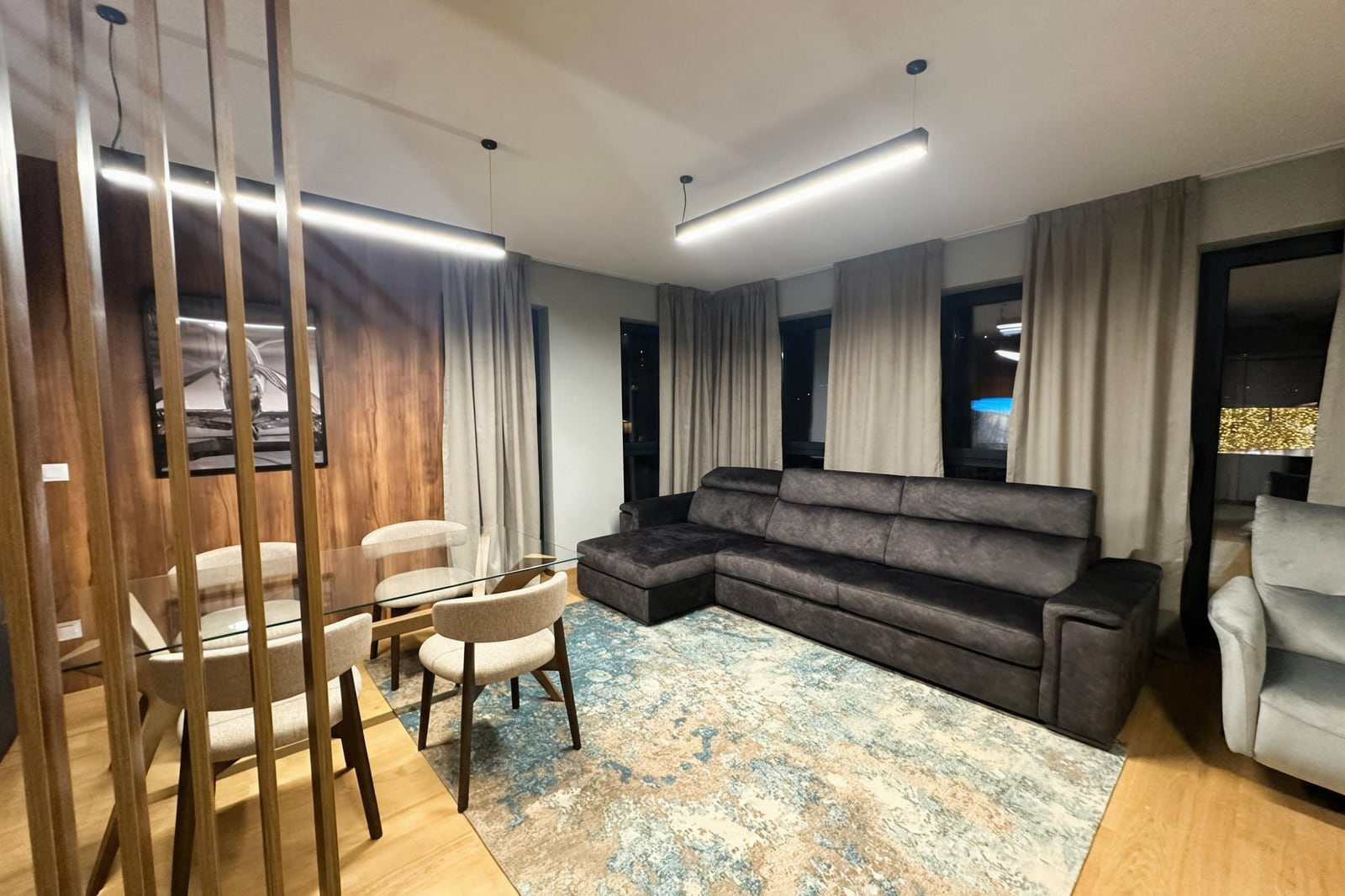 Modern living room with a large gray sofa and dining area in an apartment in Budva, Montenegro