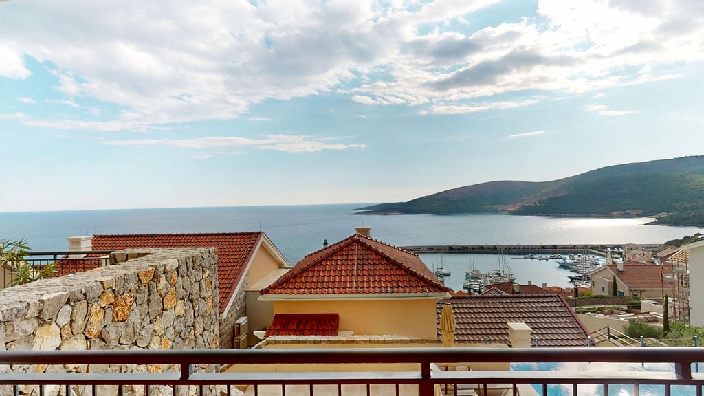 Karadağ, Luštica Bay konut kompleksinde balkondan deniz, yat marinası ve kiremit çatılı evlerin manzarası.