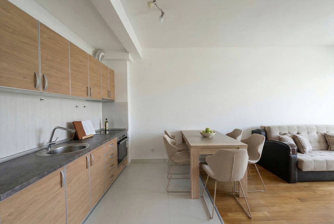 Kitchen-living room with wooden furniture and dining area in an apartment in Bečići, Montenegro.