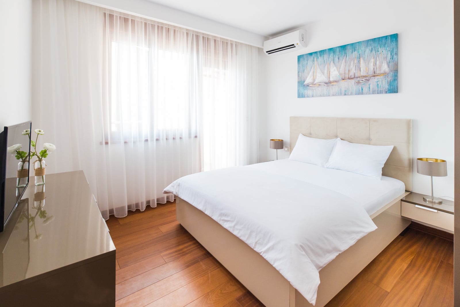 Helles Schlafzimmer mit Doppelbett und Parkettboden in einer zum Verkauf stehenden Wohnung in Bečići, Montenegro.