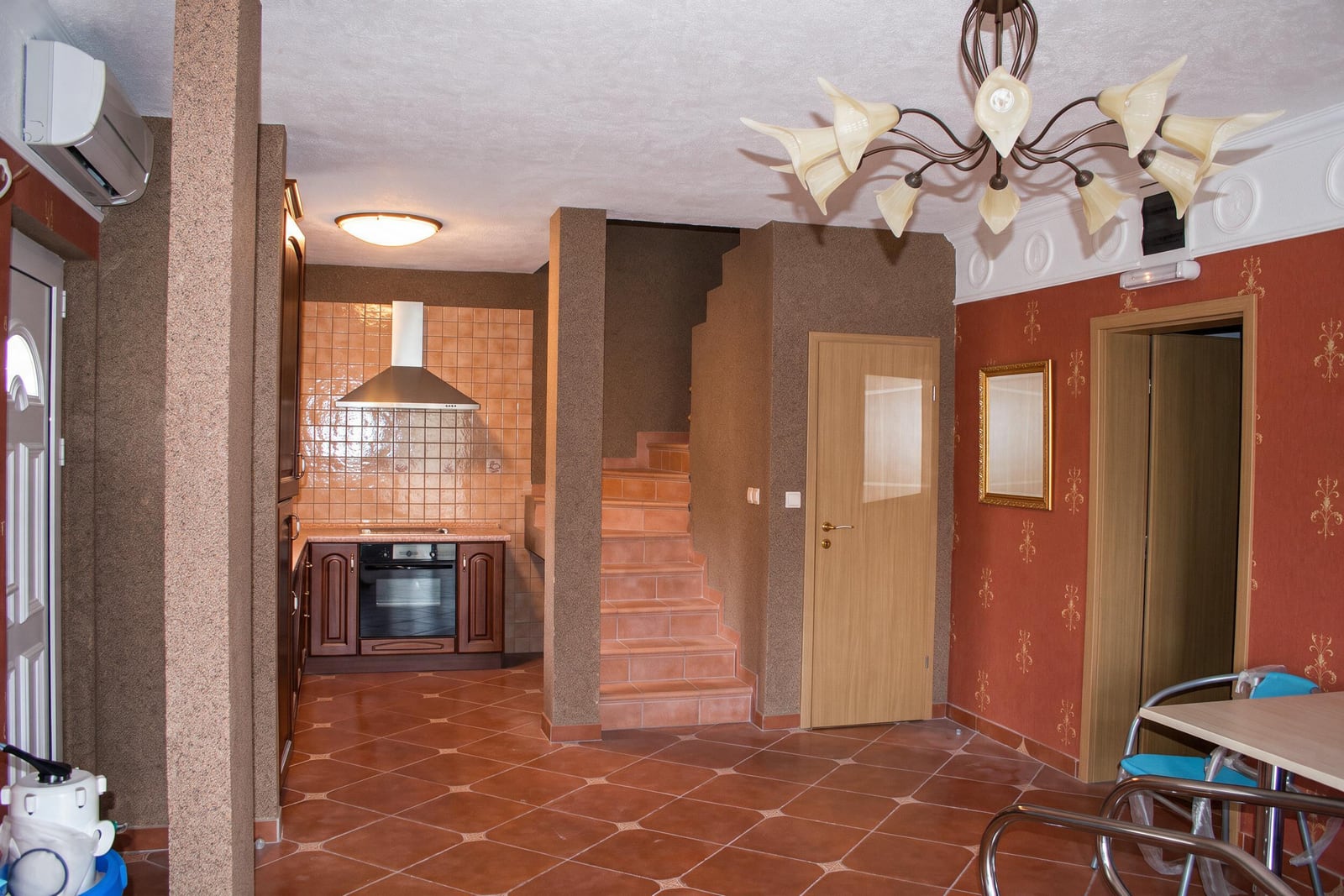 Kitchen with furniture and built-in appliances, staircase, and terracotta tiles in a house in Tivat, Montenegro