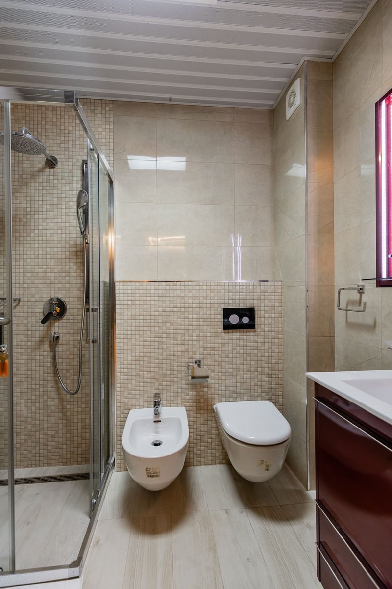 Modernes Badezimmer im Penthouse in Pržno, Montenegro: Duschkabine, Hänge-WC und Bidet, beige Fliesen.
