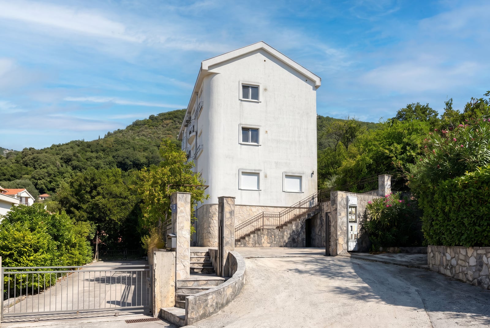 Bela trokatna stambena zgrada sa kamenom fasadom i zelenim dvorištem u Tivtu, Crna Gora