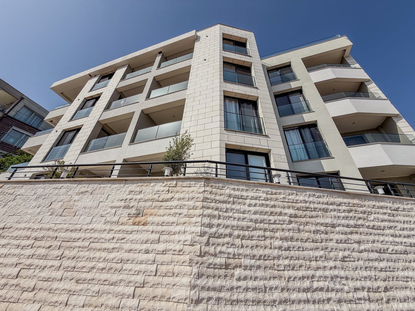 Modern apartment building with panoramic balconies and a stone facade in Budva, Montenegro