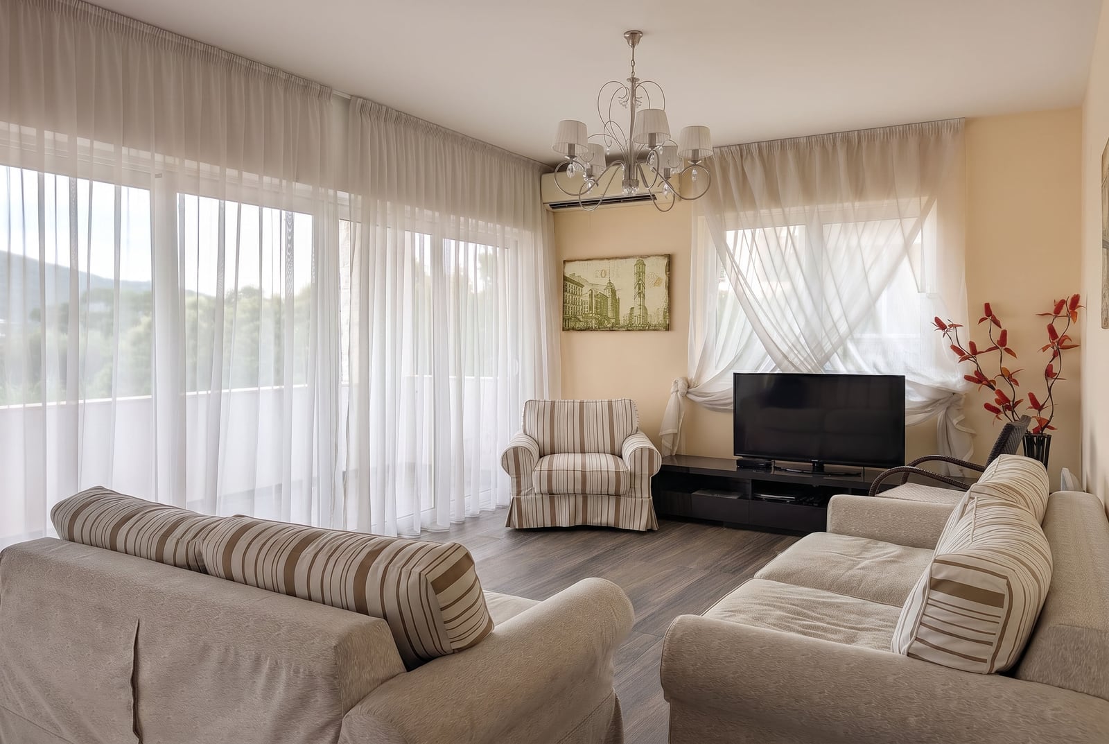 Bright living room with floor-to-ceiling windows in an apartment, Kumbor, Montenegro: upholstered furniture, TV area, and nature views.