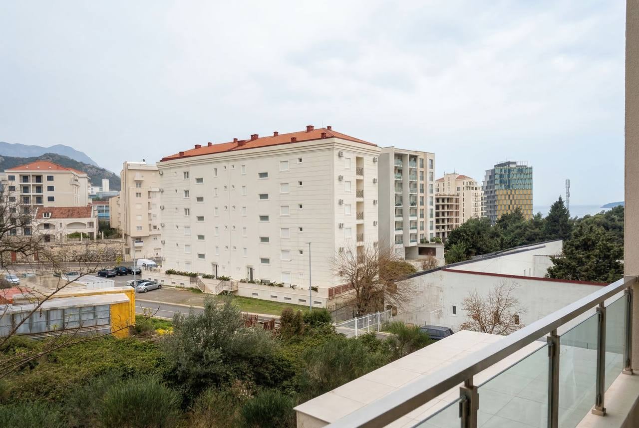 View from the balcony of an apartment in Bečići, Montenegro: urban development, green spaces, and the sea horizon.