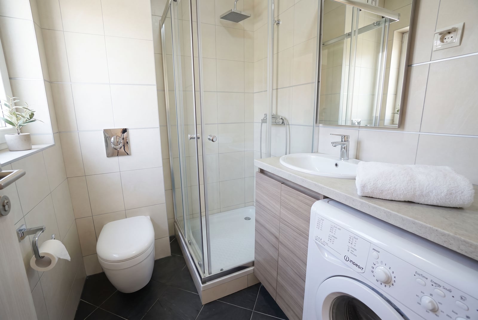 Modernes Badezimmer mit Dusche, Waschbecken, Waschmaschine und hellen Fliesen in einer Wohnung in Budva, Montenegro