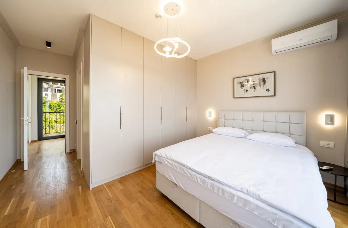 Chambre moderne avec lit double et placard intégré dans une villa à Reževići, Monténégro, avec accès au balcon.