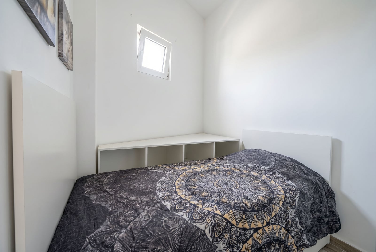 Kompaktes Schlafzimmer mit weißen Möbeln und Bett in einer Wohnung in Bečići, Montenegro. Helles Interieur, kleines Fenster.