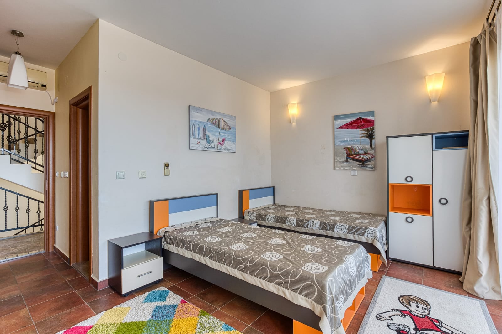 Chambre avec deux lits, armoire et décoration lumineuse dans une villa à Bečići, Monténégro. Intérieur confortable pour se détendre.