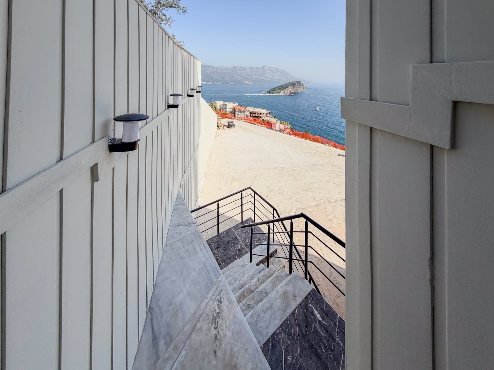 Marble staircase and white wall with lighting, panoramic view of the sea and island in Budva, Montenegro