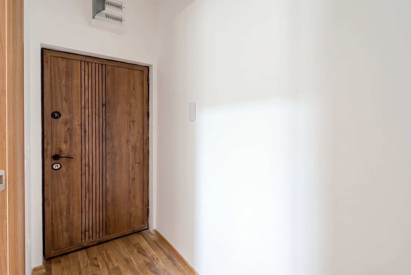 Modern wood-look entrance door and white walls in the hallway of an apartment in Budva, Montenegro