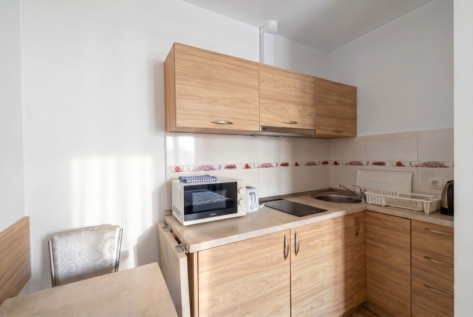 Compact kitchen with wooden cabinets and appliances in an apartment for sale in Becici, Montenegro.