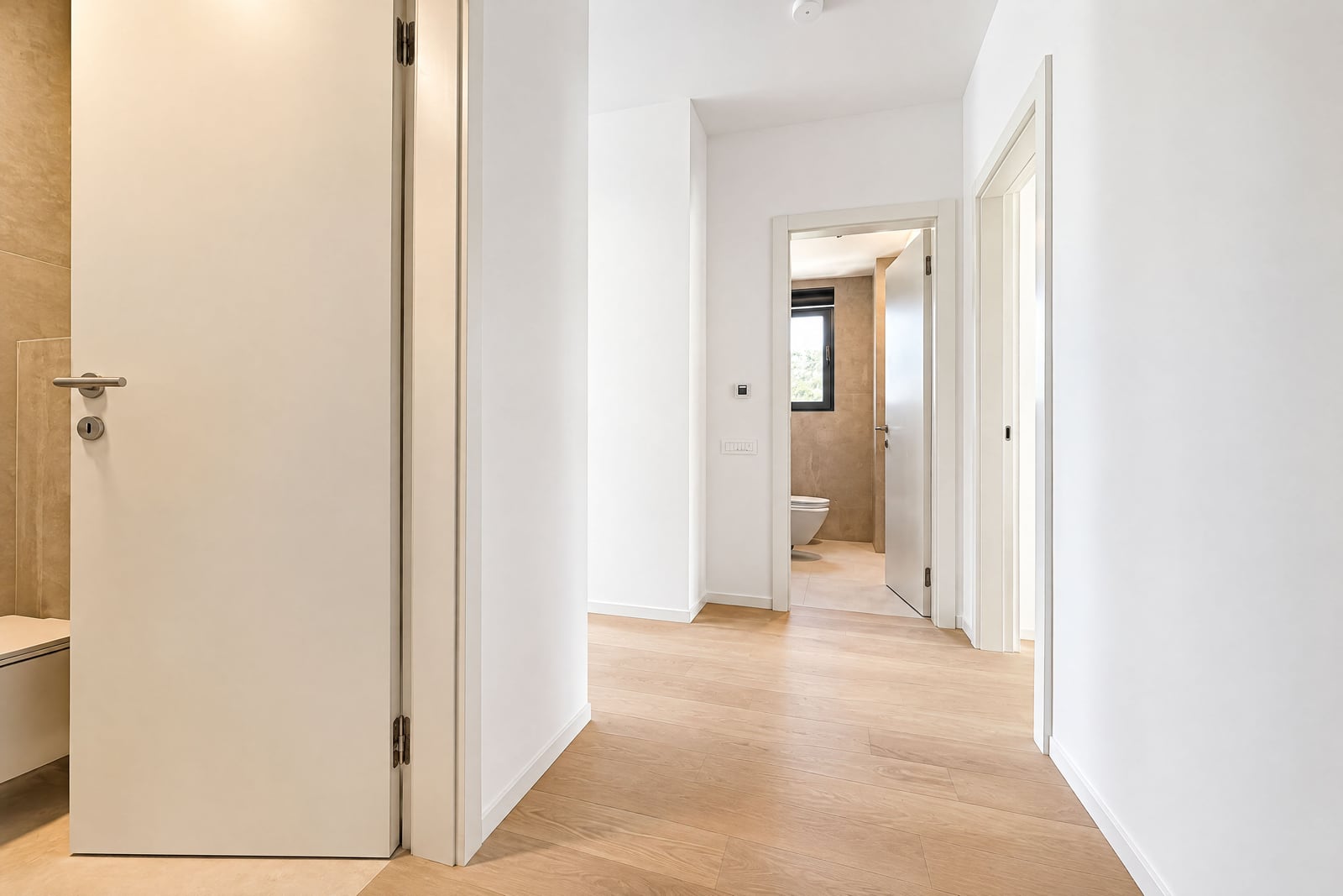 Bright hallway with white interior doors and laminate flooring in a new apartment in Becici, Montenegro