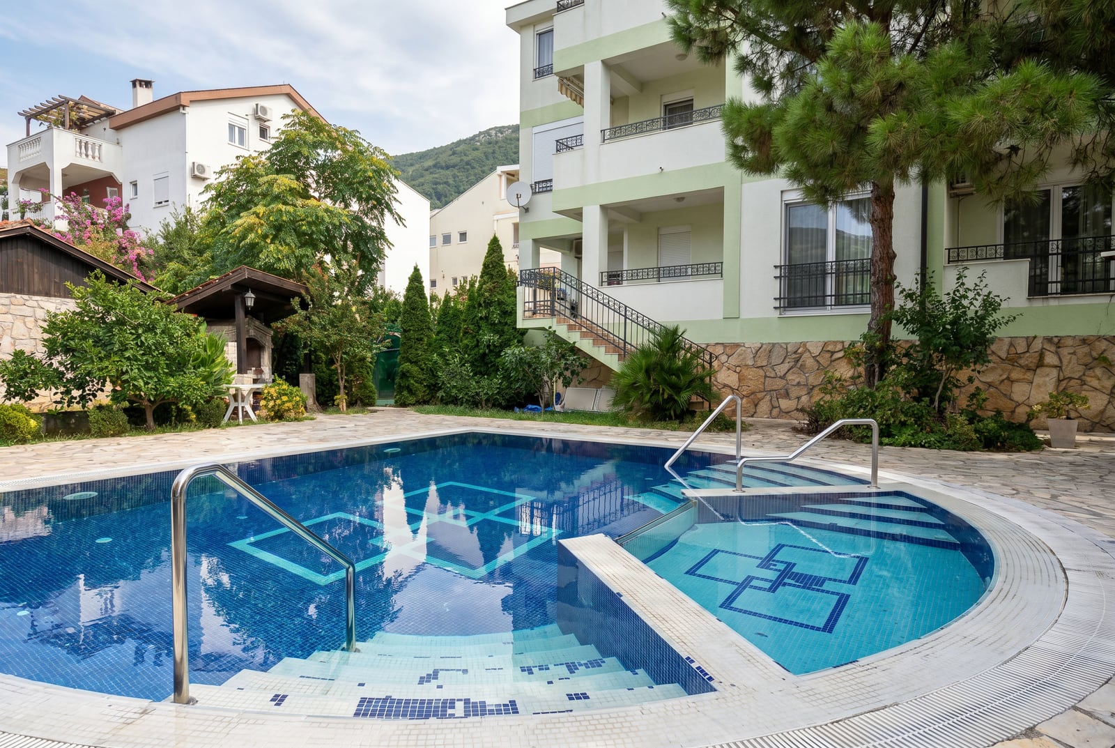 Karadağ, Budva'da bir konut projesinde dinlenme alanı, barbekü ve peyzaj düzenlemesine sahip açık yüzme havuzu.