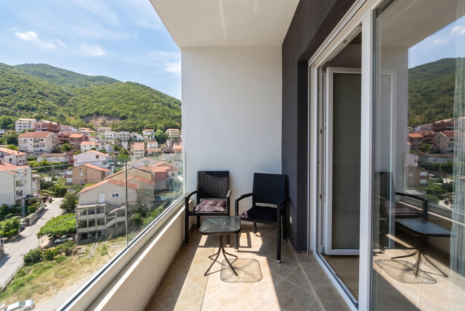 Balkon sa pletenim nameštajem i panoramskim pogledom na planine i grad Budvu, Crna Gora u modernom apartmanu br. 2745.