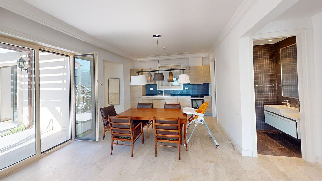 Moderna kuhinja-trpezarija sa drvenim stolom i izlazom na terasu u apartmanima, Luštica, Crna Gora.