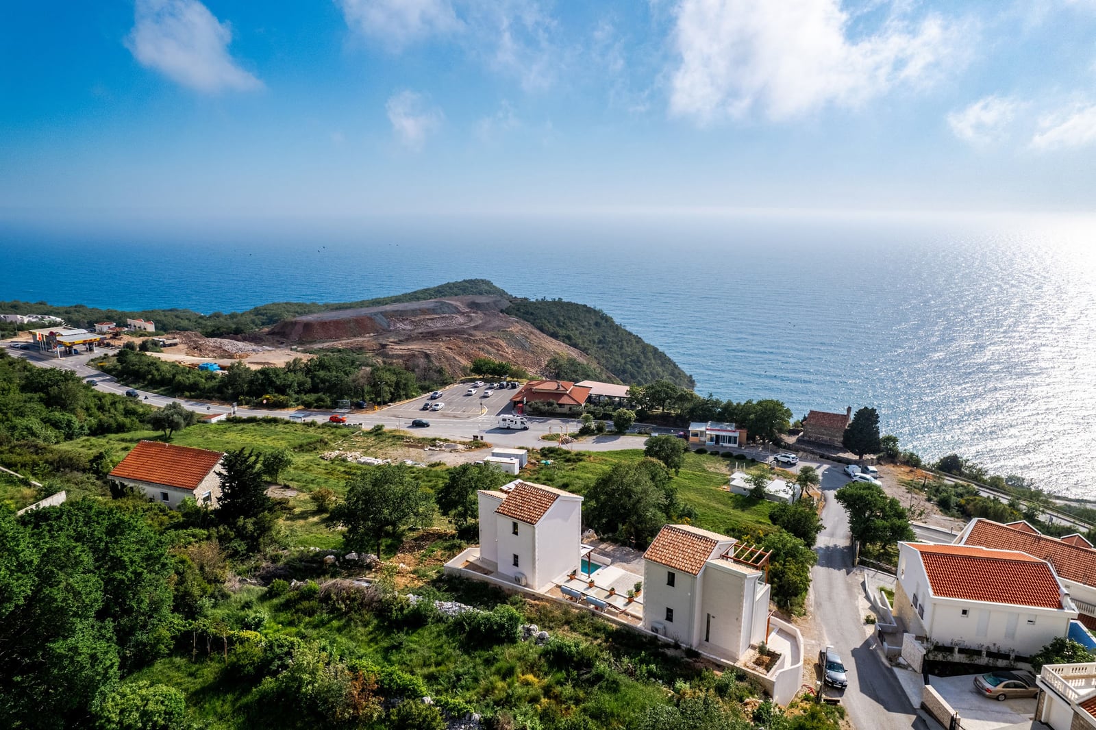 Pogled odozgo na kompleks vila sa krovovima od crepa u Blizikuči, Crna Gora, sa morem u pozadini