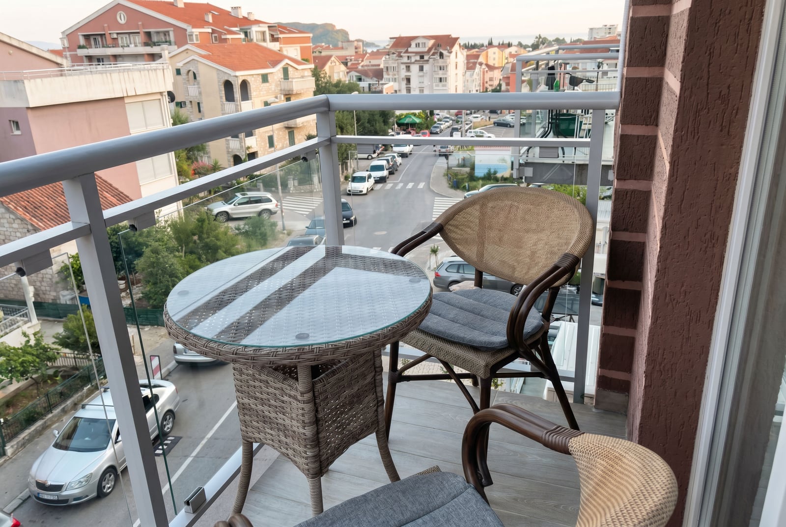 Prijatni balkon sa pletenim nameštajem i pogledom na grad u stanu u Budvi, Crna Gora.