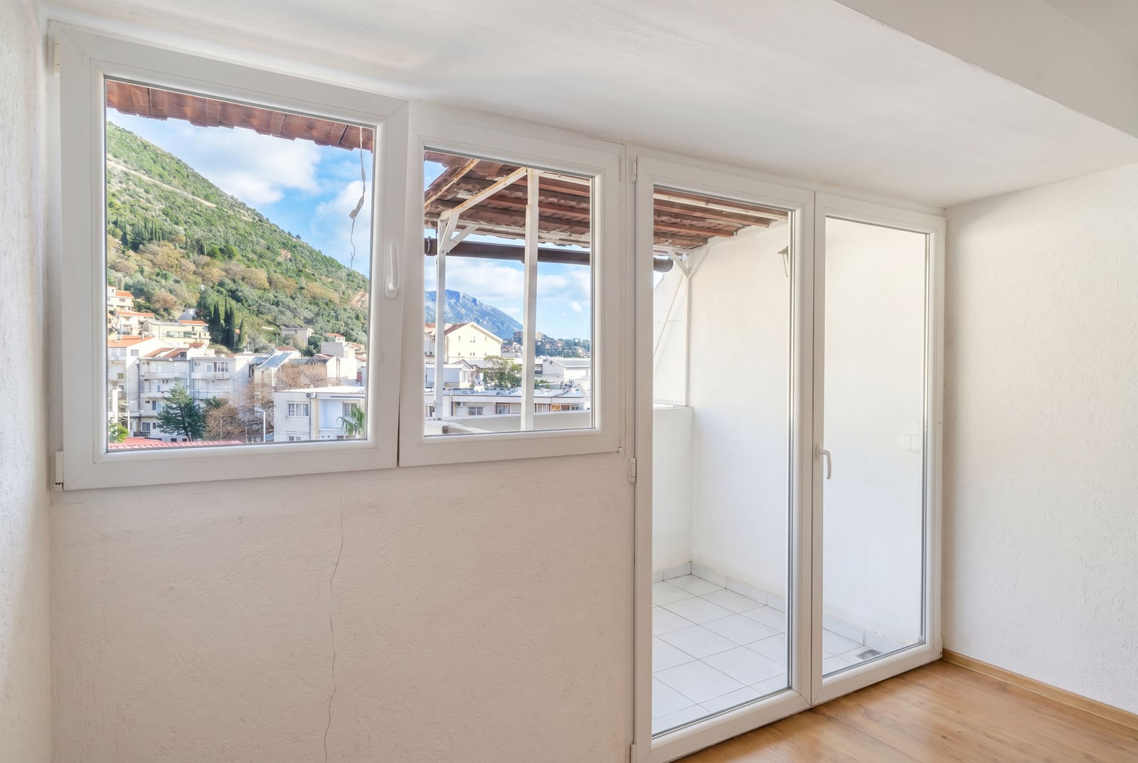 Bright living room in a Budva, Montenegro apartment, with balcony access and panoramic views of the mountains and the city.