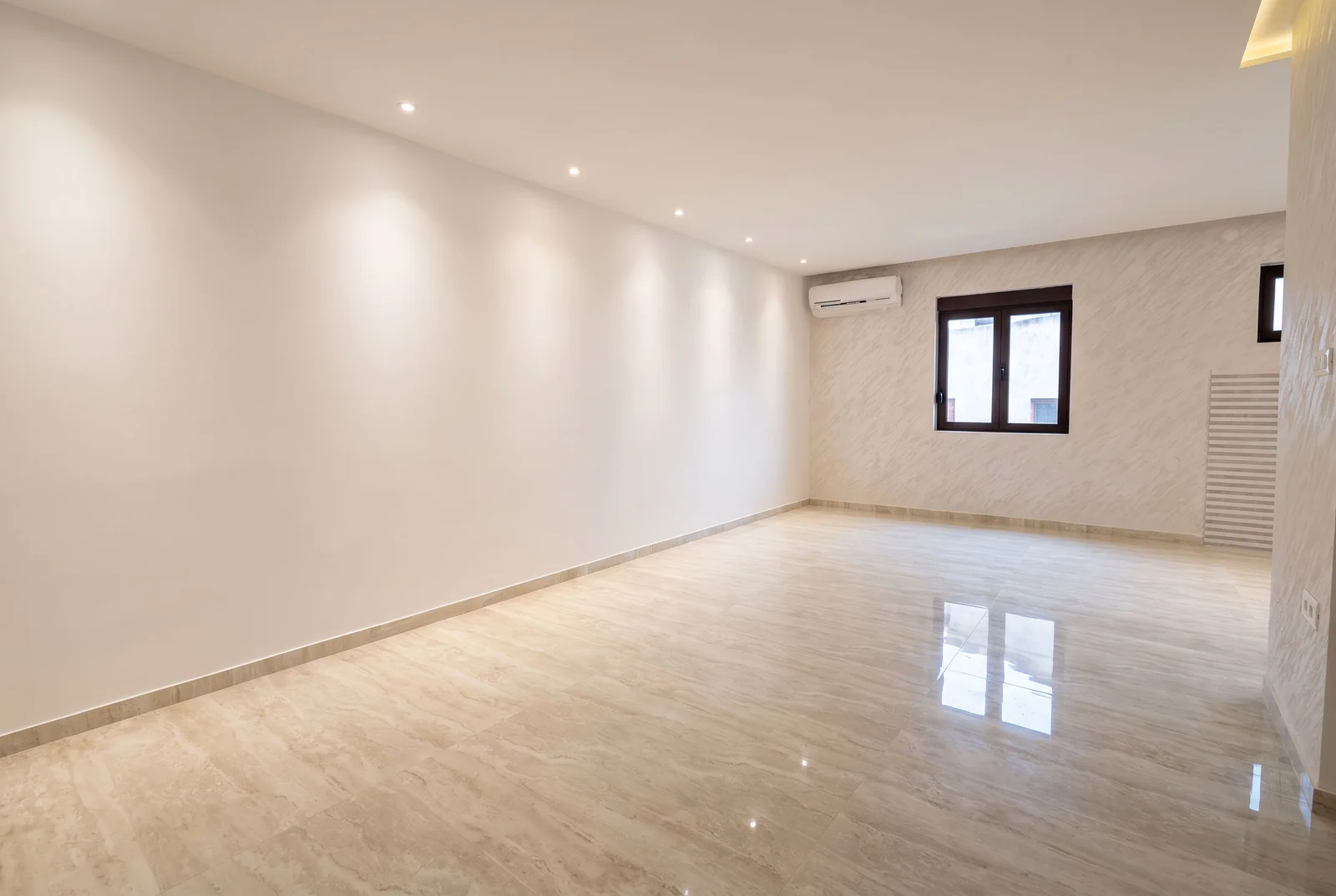 Empty room with glossy light floor, white walls, a window, and an air conditioning unit.