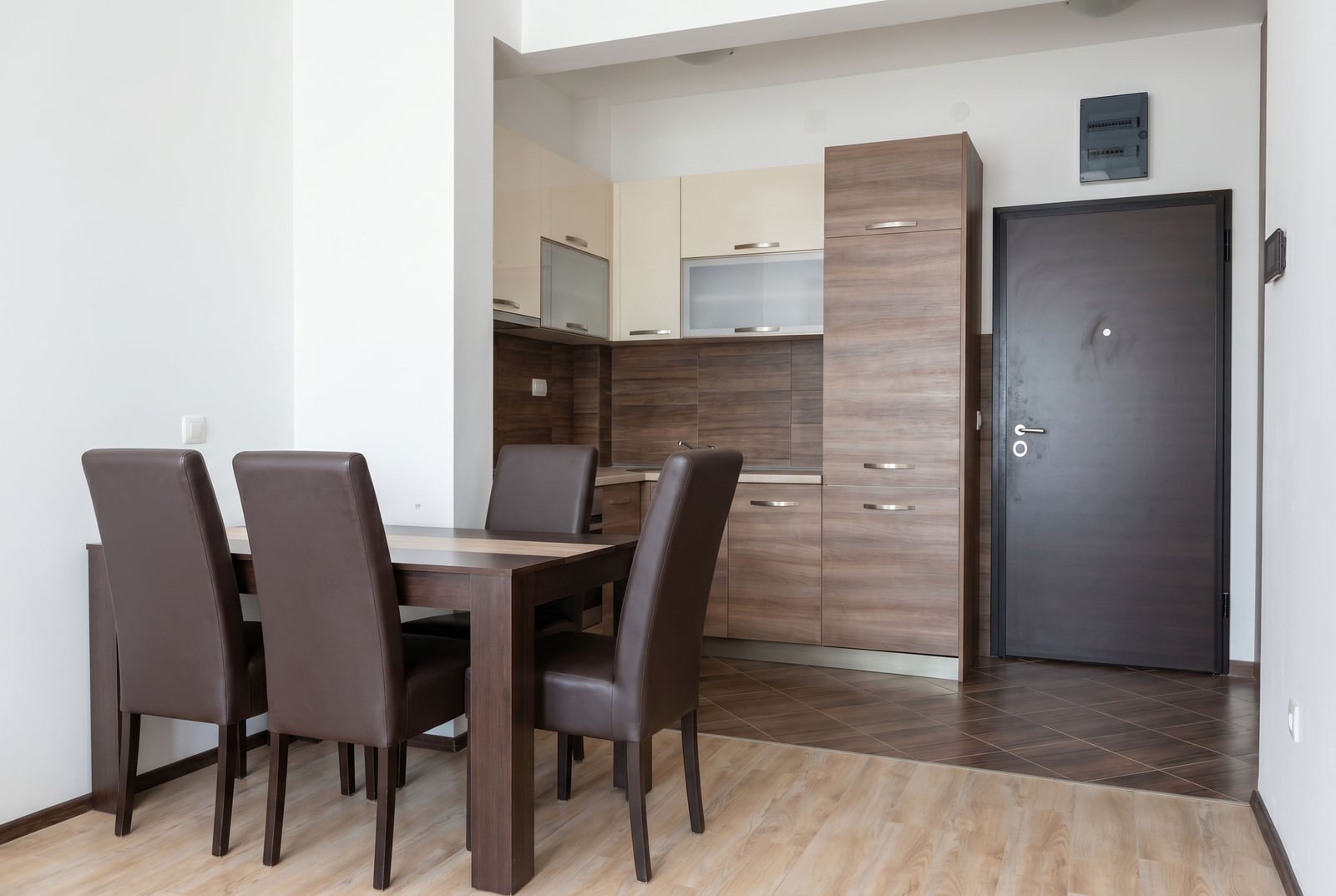 Modern kitchen-dining room in a Budva apartment, Montenegro: dining area, kitchen cabinetry, and dark front door.