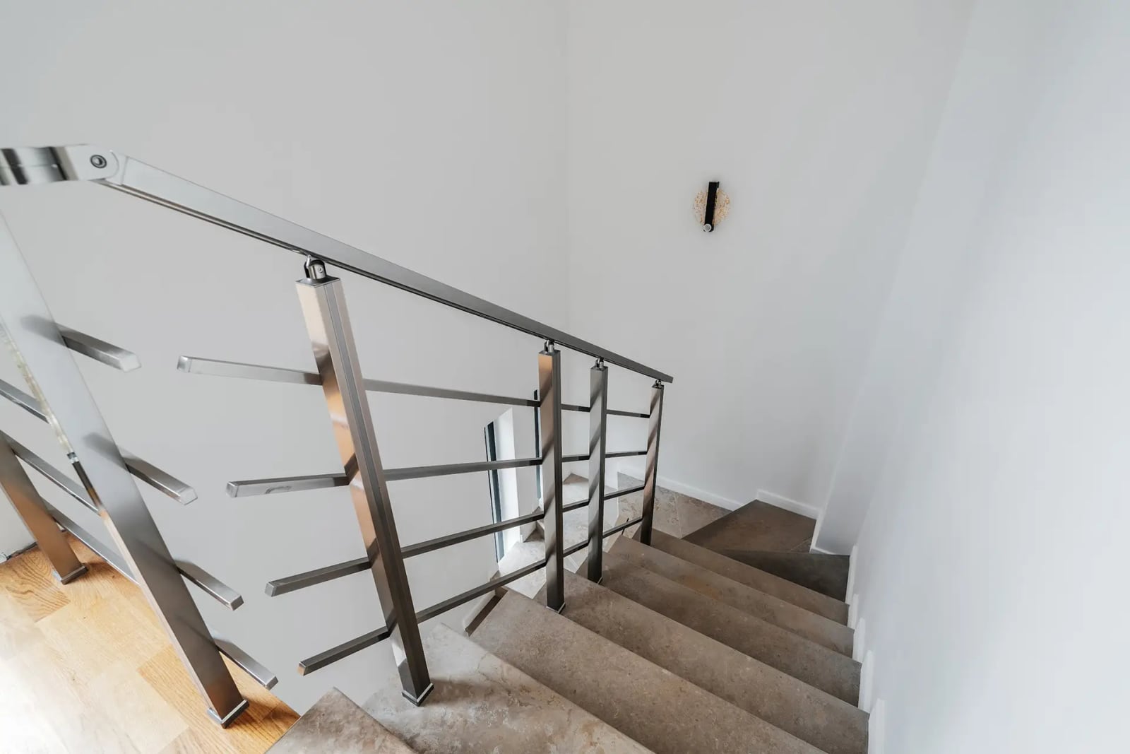 Modern staircase with metal railings in a villa interior in Reževići, Montenegro. Stone steps and light-colored walls.
