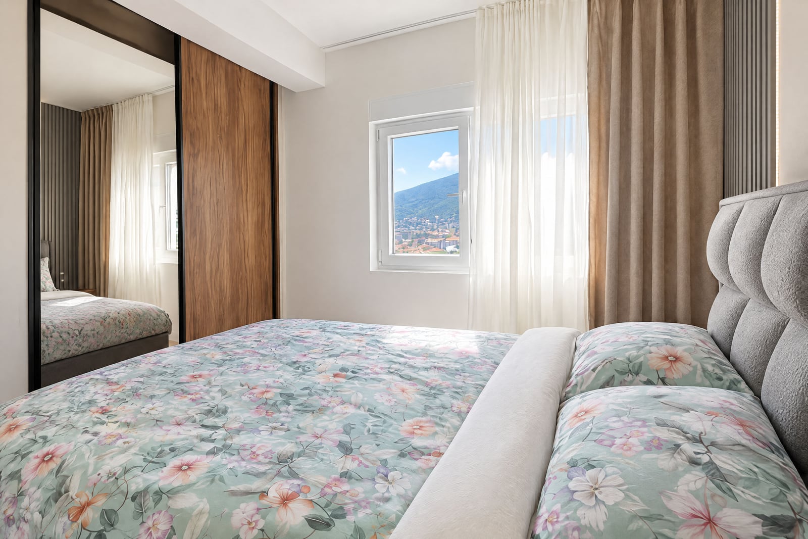 Modern bedroom with a soft bed, a built-in wardrobe, and mountain views in an apartment in Budva, Montenegro