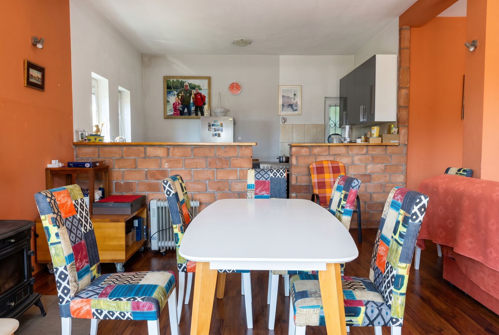 Living room with dining area and brick partition in a house, Buljarica, Montenegro: vibrant chairs and a modern kitchen.