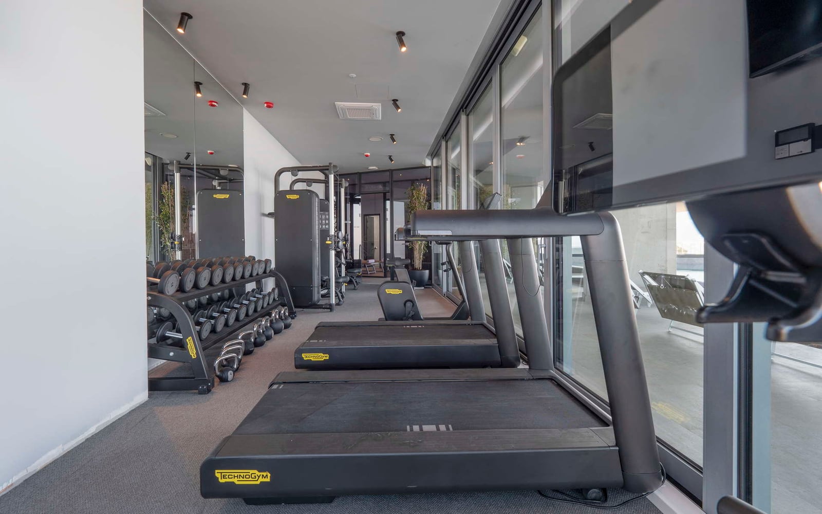 Moderna teretana sa panoramskim prozorima i spravama Technogym u hotelu u Bečićima, Crna Gora