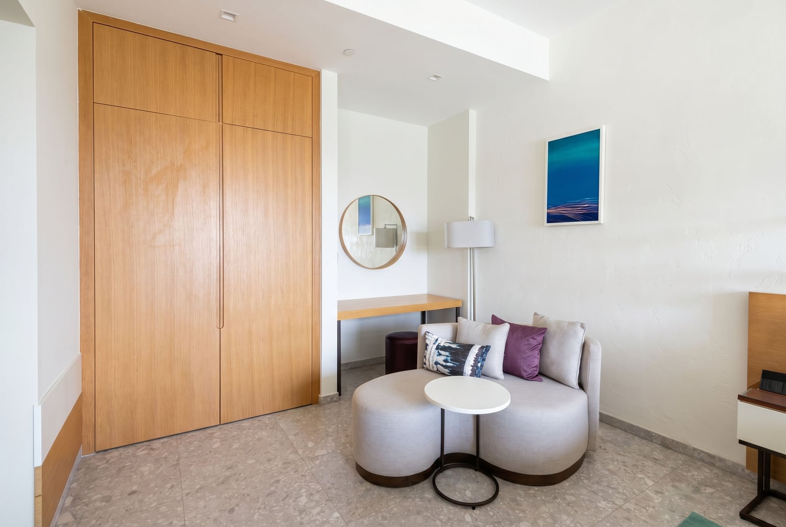 Modernes Schlafzimmer im Hotel Luštica Bay, Montenegro: helle Möbel, Einbauschrank und Ruhebereich mit Sessel.