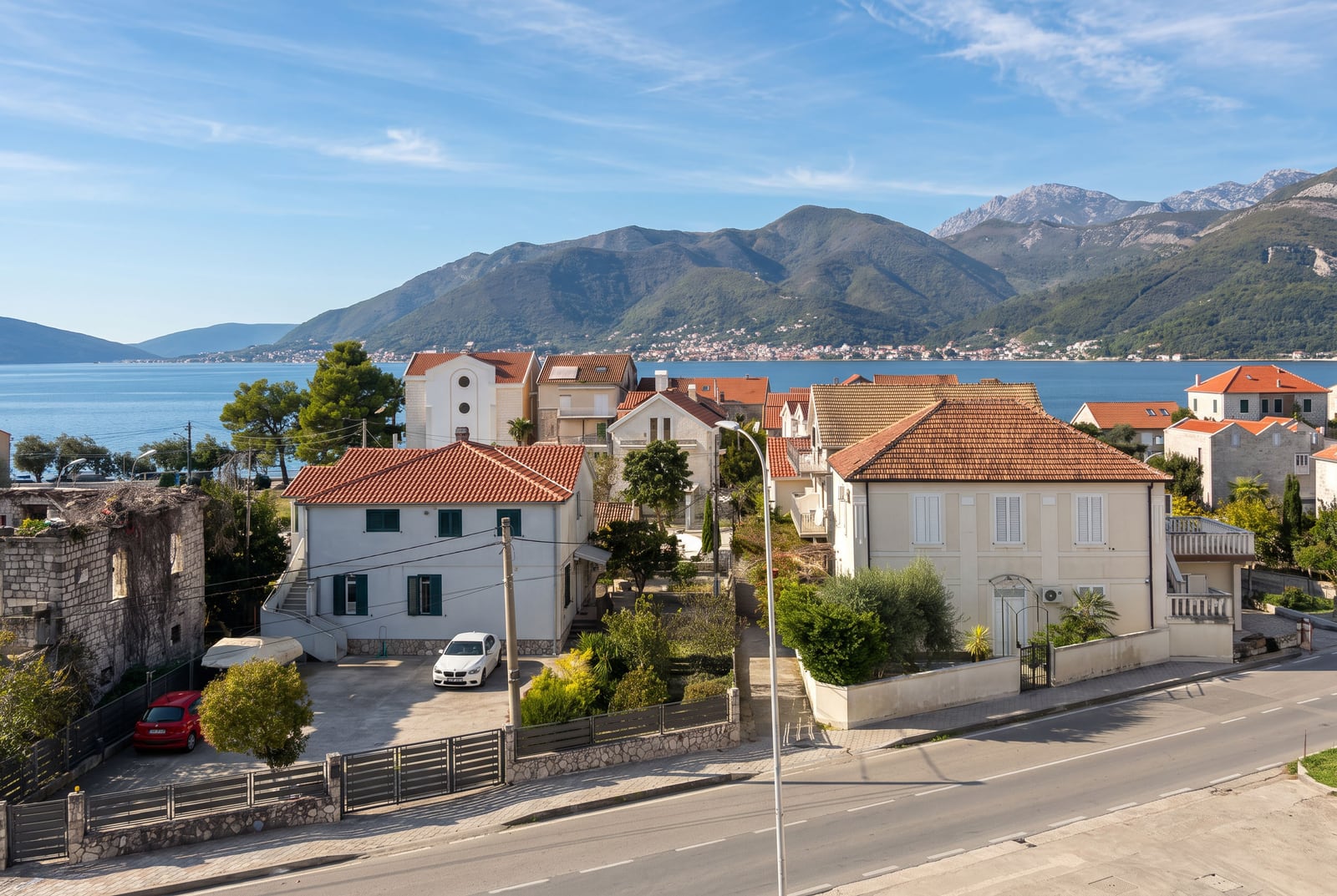 Pogled na kuće sa krovovima od crijepa, zaliv i planine u gradu Tivat, Crna Gora