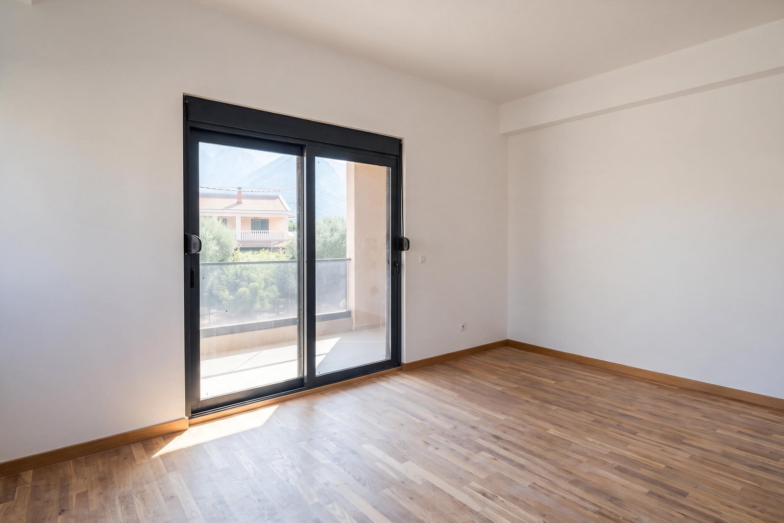Bright bedroom with parquet flooring and balcony access in an apartment in the city of Bar, Montenegro. Panoramic door with mountain views.