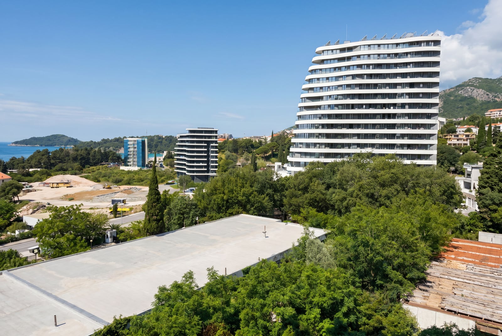 Modern residential complexes in Bečići, Montenegro: view of high-rise buildings, greenery, and the coastline.
