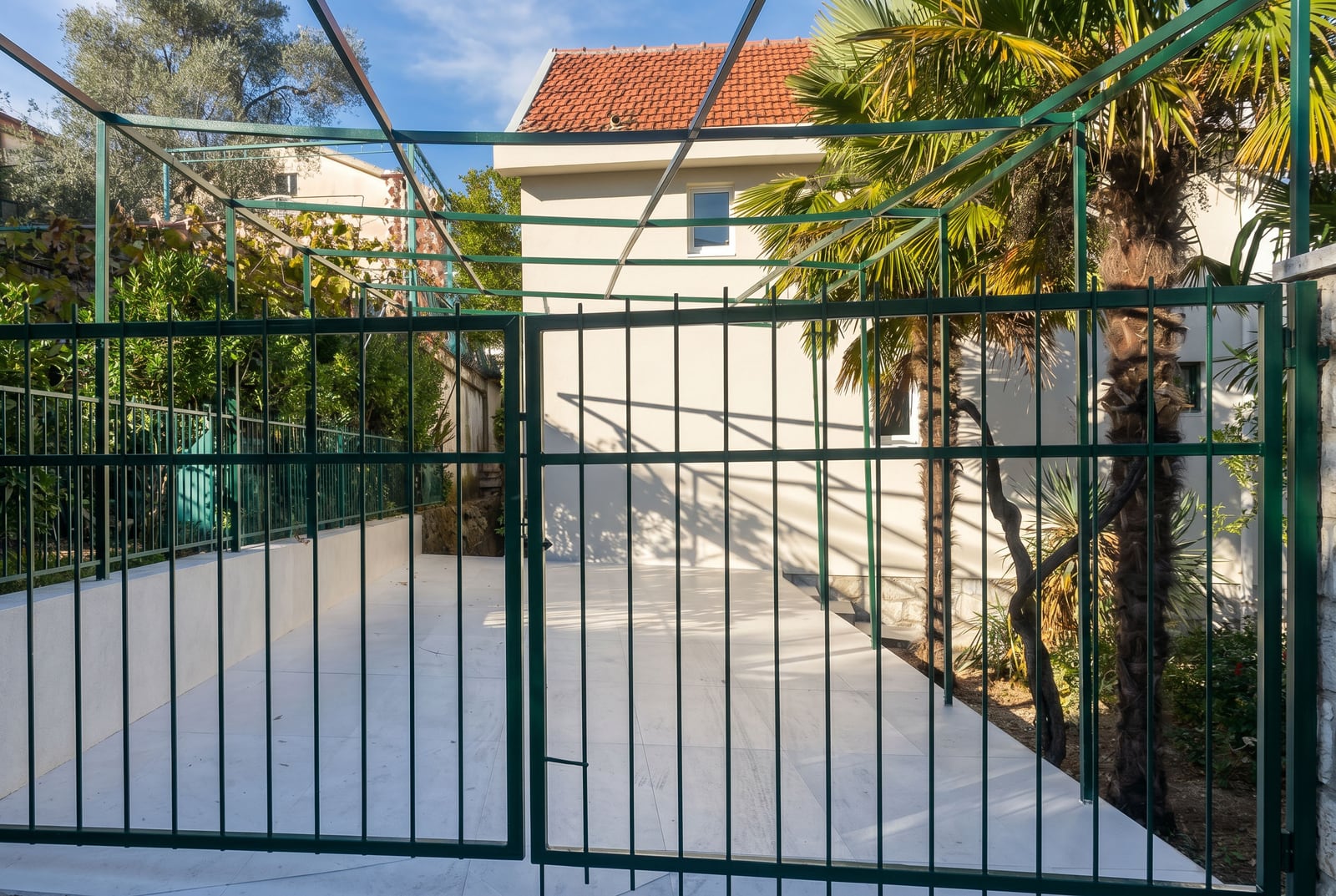Parking privé avec abri et portail métallique devant une maison à Krašići, Monténégro.