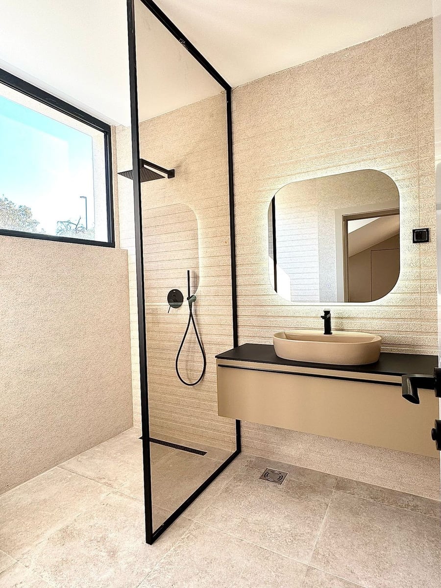 Salle de bain moderne dans une villa à Kamenovo, Monténégro : douche avec profil noir, vasque posée et miroir.