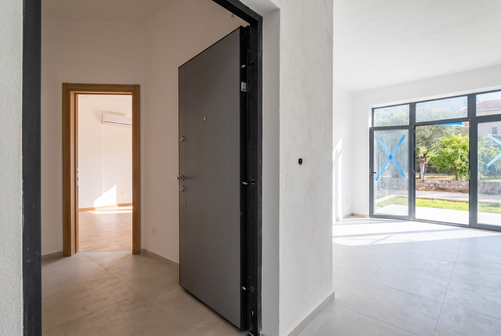 Interior of a new apartment in Bar, Montenegro: entrance door, bright living room with panoramic windows and access to the terrace.
