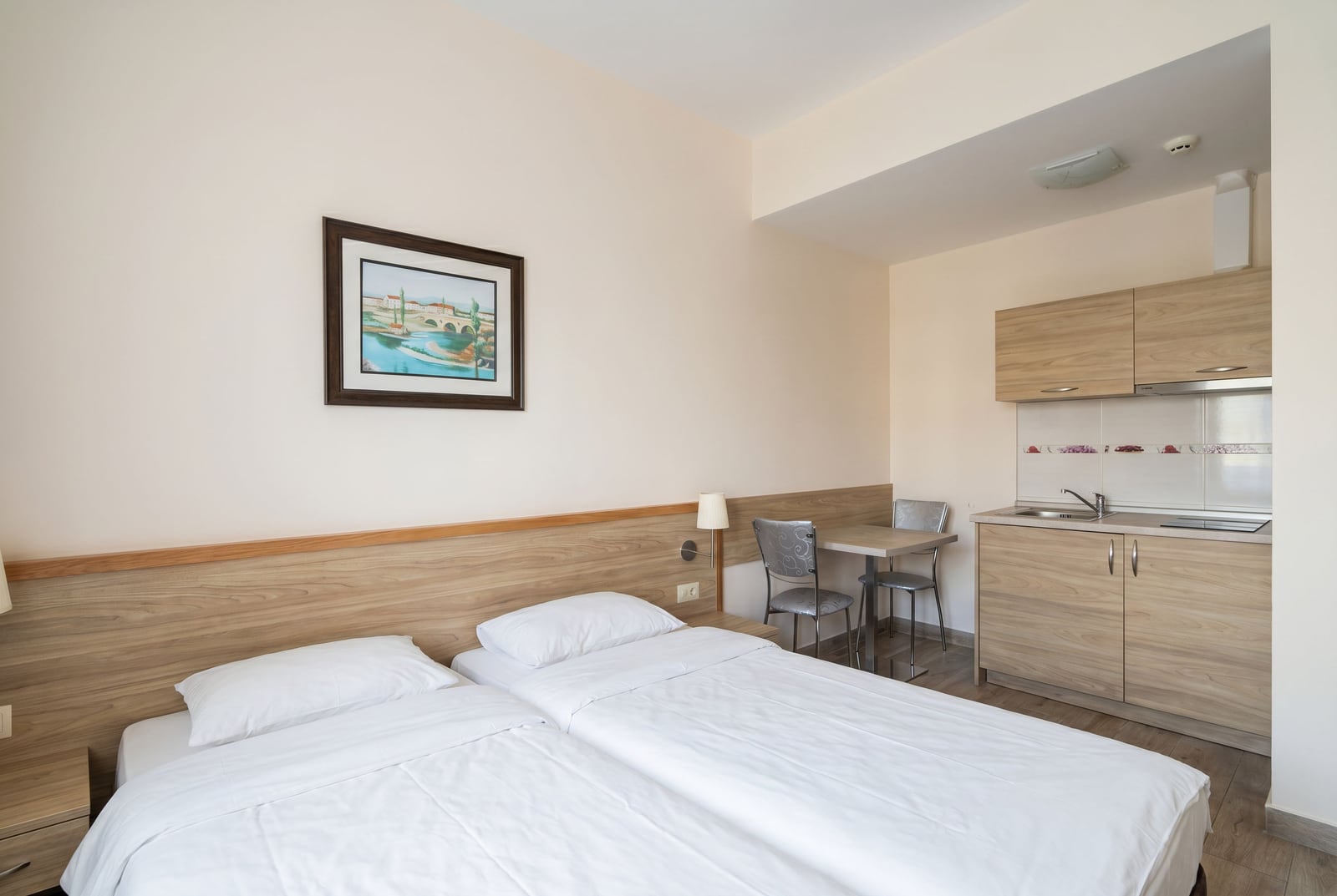 Interior of a bedroom with a kitchen in an apartment in Bečići, Montenegro: double bed, dining area, and light-toned finishes.