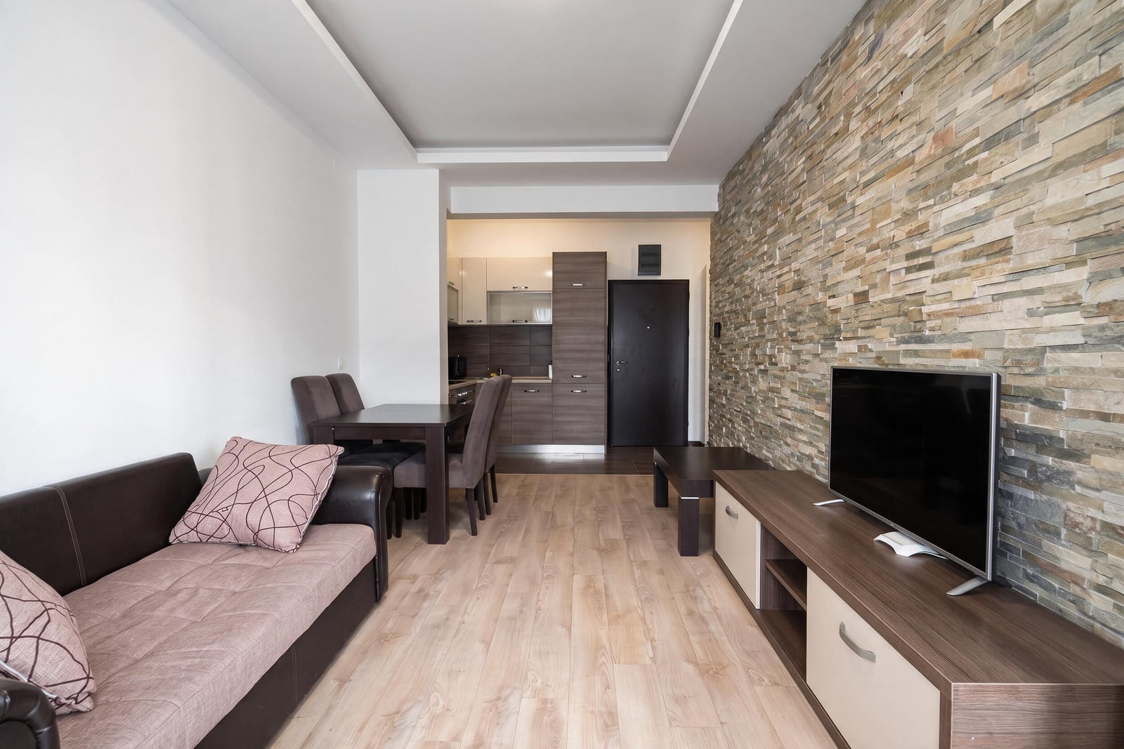 Modernes Wohnzimmer mit Steinwand, Sofa und Küche in einer Wohnung in Budva, Montenegro